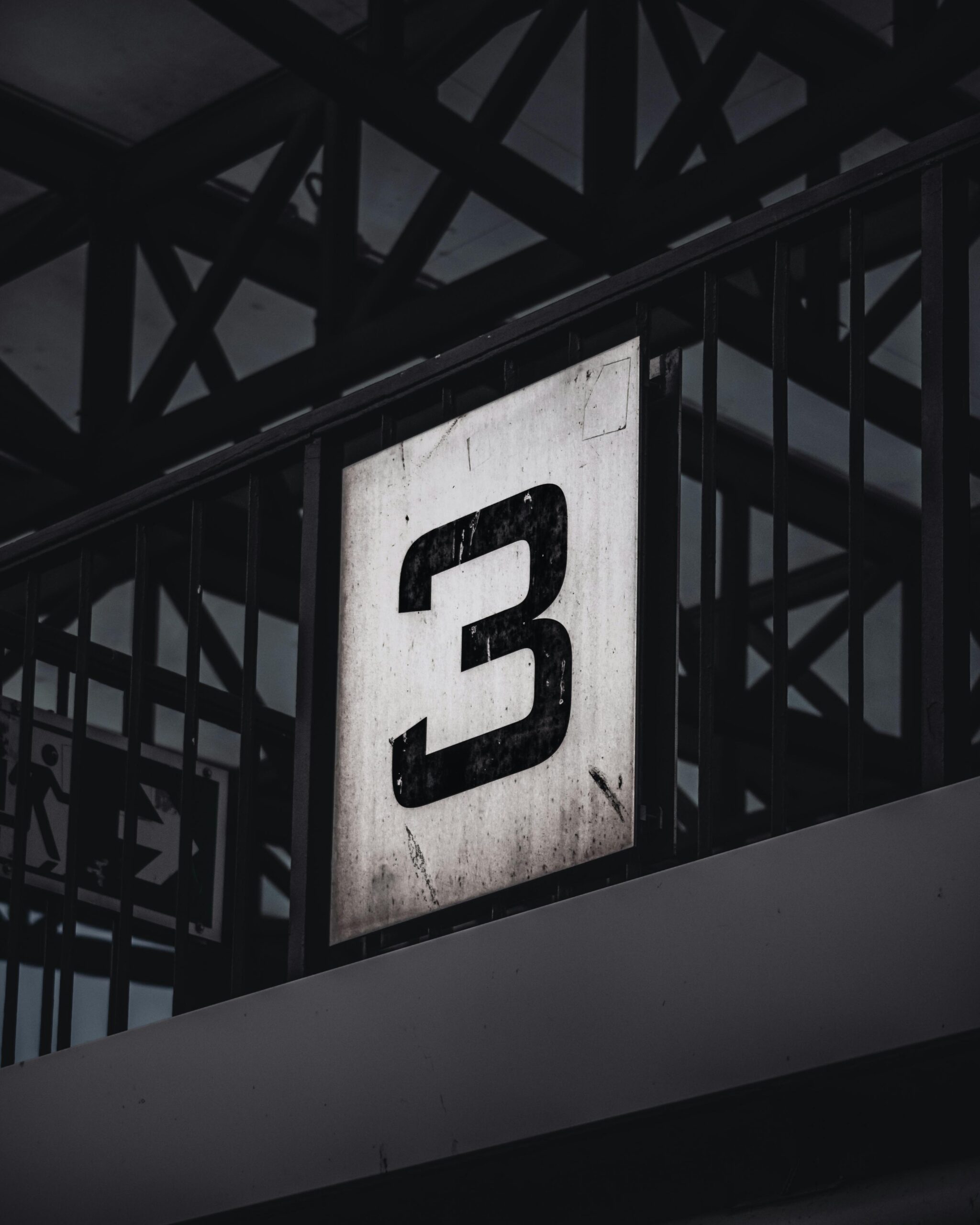 Close-up of a number 3 sign in a Hamburg station with industrial framework.