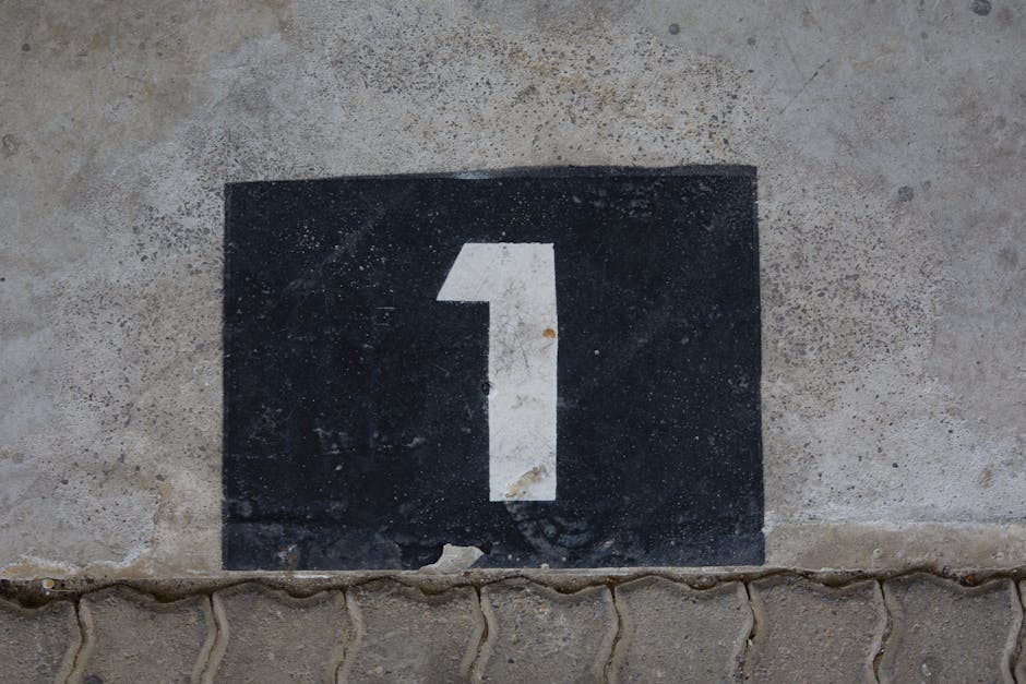 A weathered concrete wall with a bold number one painted on a black rectangular background.